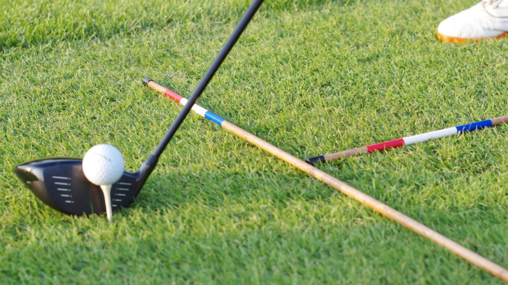 A picture of golf alignment sticks on the ground with a golf ball and club